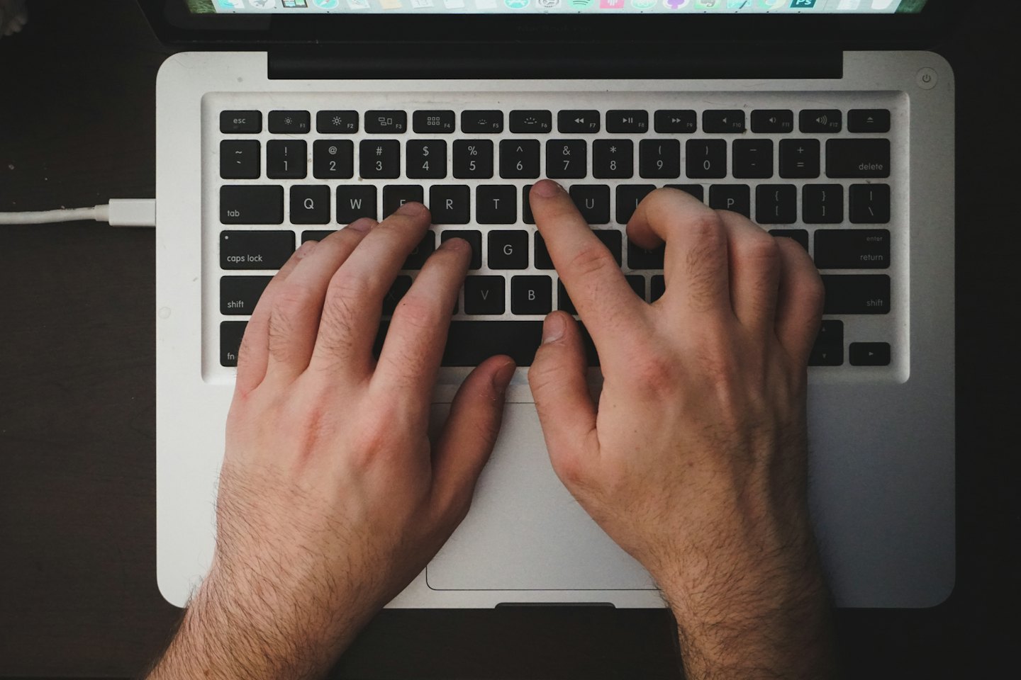 Hände tippen auf einer Laptop-Tastatur mit sichtbarem Bildschirm.